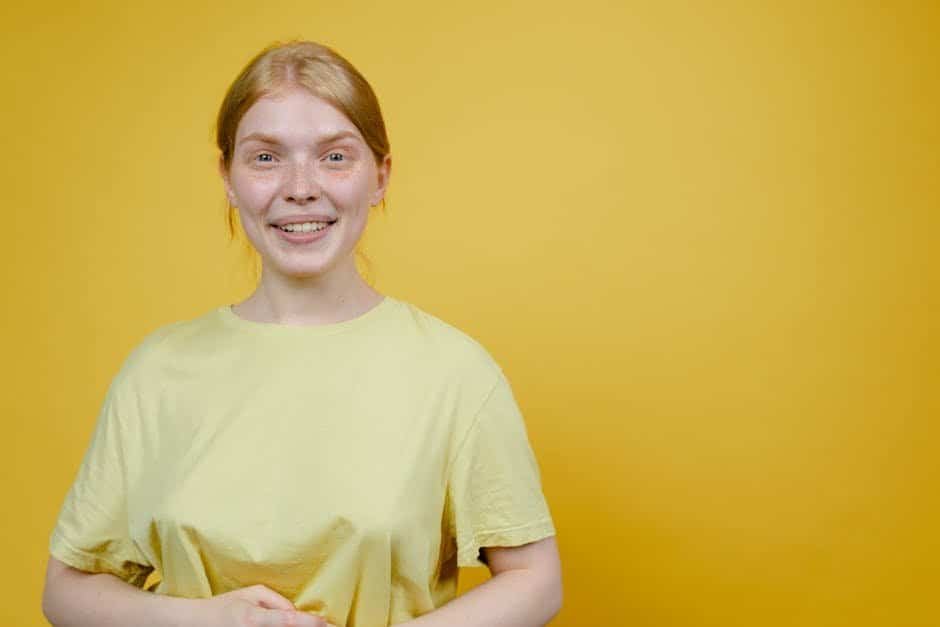 Smiling woman wearing a yellow T-shirt against a yellow background.