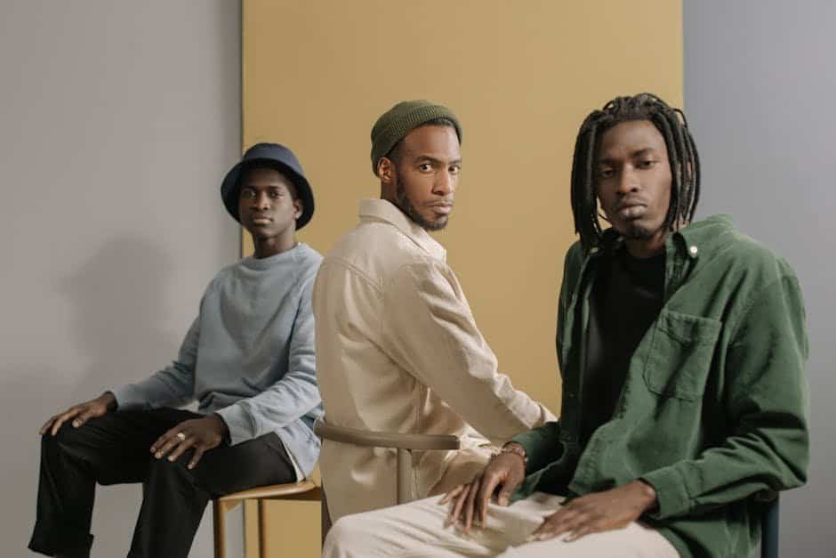 Three stylish men wearing casual outfits sit against a yellow and gray background.