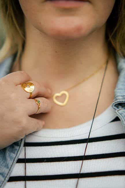 Close-up of a woman wearing a heart-shaped necklace and rings, casual style.