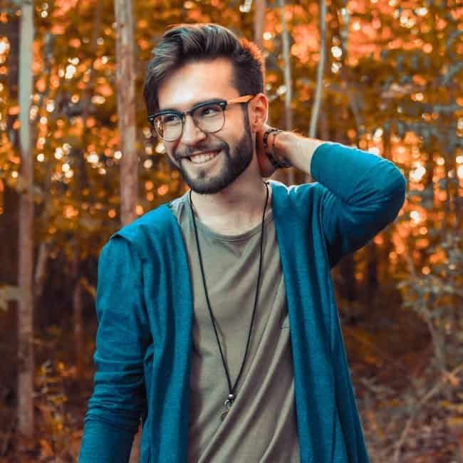 The Psychology of Colorful Shirts: What Your Outfit Says About You Smiling man with glasses in casual outfit in autumn forest setting.